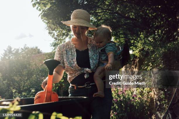 mother and baby girl taking water from rainwater tank. - rainwater tank stock pictures, royalty-free photos & images