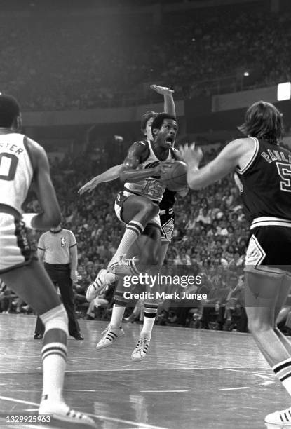 Denver Nuggets guard Jim Price drives between San Antonio spurs forward Mark Olberding and center Billy Paultz during an NBA basketball game at...