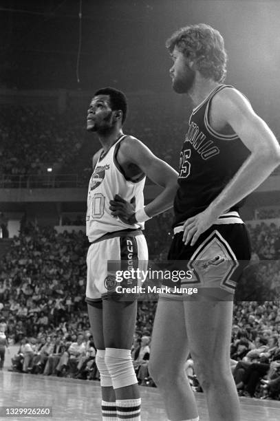 Coby Dietrick, a 6’10” San Antonio center and Denver Nuggets 7’1” center Marvin Webster stand along the lane waiting to rebound a free throw during...