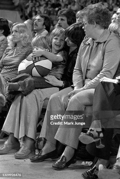 Young fan sits on his mother’s lap holding an ABA red-white-and-blue basketball during an NBA basketball game between the Denver Nuggets and the San...