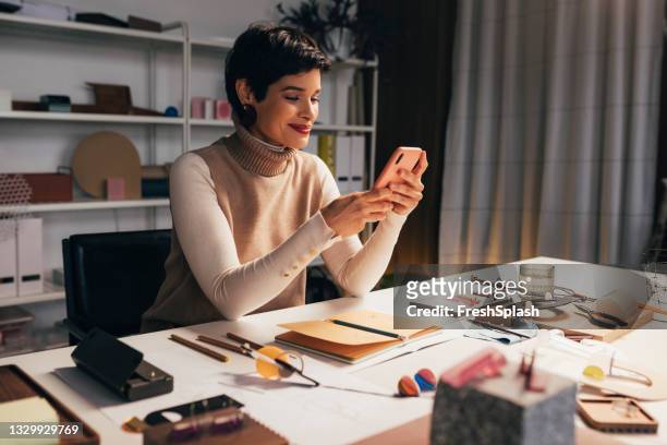 beautiful young woman using her smartphone at work - jewellery designer stock pictures, royalty-free photos & images