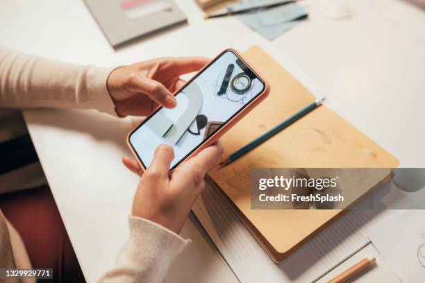 anonymous female architect browsing the web on her mobile phone for inspiration - web designer stockfoto's en -beelden