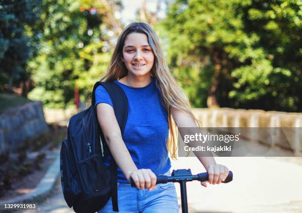 student girl with mask riding scooter to the school - girl riding scooter stock pictures, royalty-free photos & images