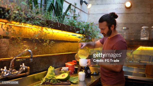 man preparing detox juice at home - avocado smoothie stock pictures, royalty-free photos & images