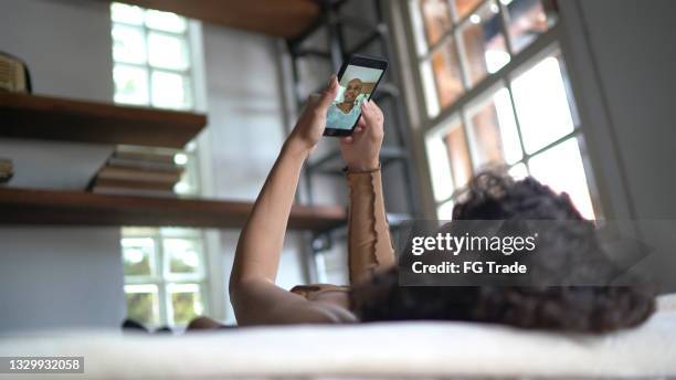 woman doing a video call on smartphone at home - long distance relationship stock pictures, royalty-free photos & images