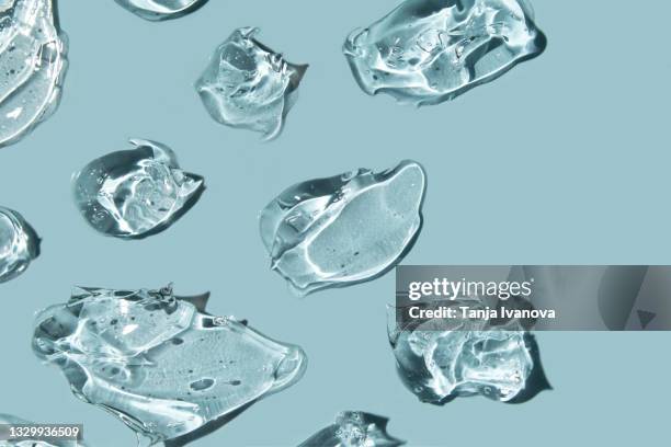transparent drops of gel on blue background. liquid hyaluronic acid gel. flat lay, top view, copy space - peptídeo imagens e fotografias de stock