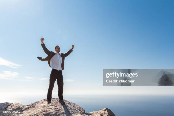 business man celebrating success against blue sky - conquering adversity stock pictures, royalty-free photos & images