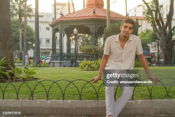 giovane ritratto maschile latino, in viaggio, seduto e in posa al parque seminario o al parco delle iguane, guayaquil, guayas, ecuador - guayaquil foto e immagini stock