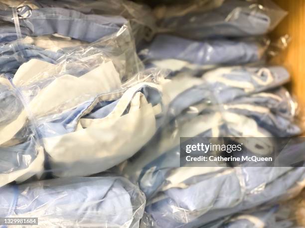 stacks of sanitized medical gowns in protective plastic wrap - operationskittel stock-fotos und bilder