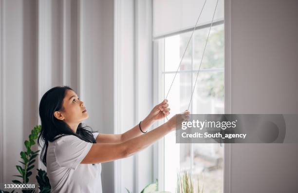 frau, die jalousien am fenster senkt - lowering stock-fotos und bilder