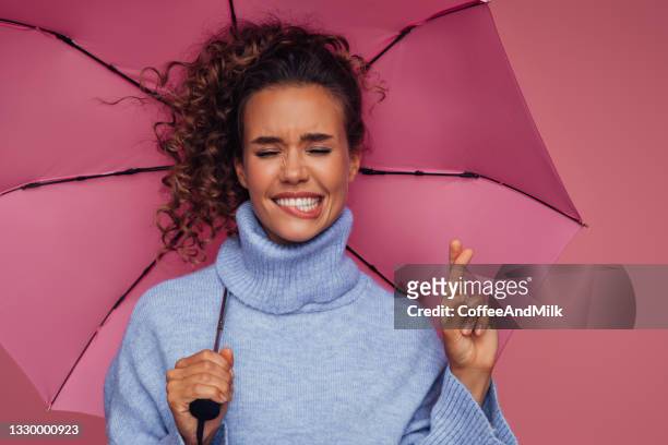 mädchen mit rosa regenschirm und hoffnungszeichen - finger kreuzen stock-fotos und bilder
