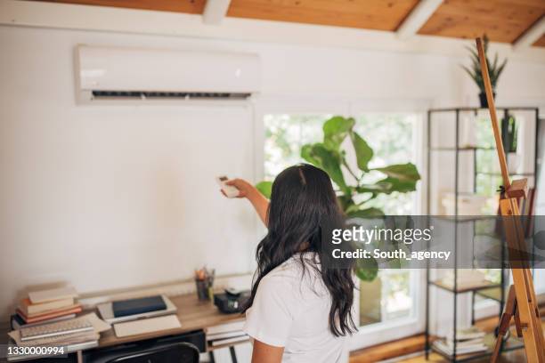 woman turning on air conditioner - ventilador imagens e fotografias de stock