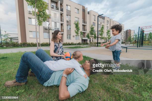 gemischtrassige familie mit zwei kindern, die im sommer draußen spielen - mixed race family stock-fotos und bilder