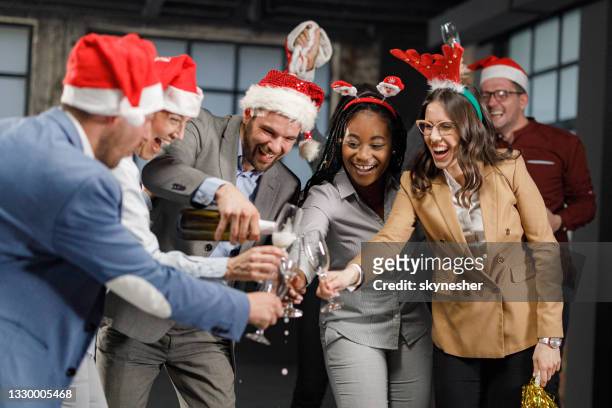glücklicher geschäftsmann, der seinen kollegen während einer weihnachtsfeier im büro champagner einschenkt. - christmas party office stock-fotos und bilder