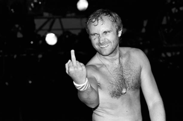 Phil Collins giving the finger while performing with Genesis at the Forest Hills Tennis Stadium in Queens, New York on August 22, 1982.