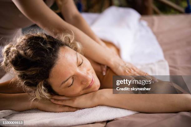 smiling woman receiving relaxed massage at the spa. - massage stock pictures, royalty-free photos & images