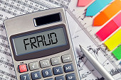 Office desktop with calculator displaying the word fraud. Business and financial crime