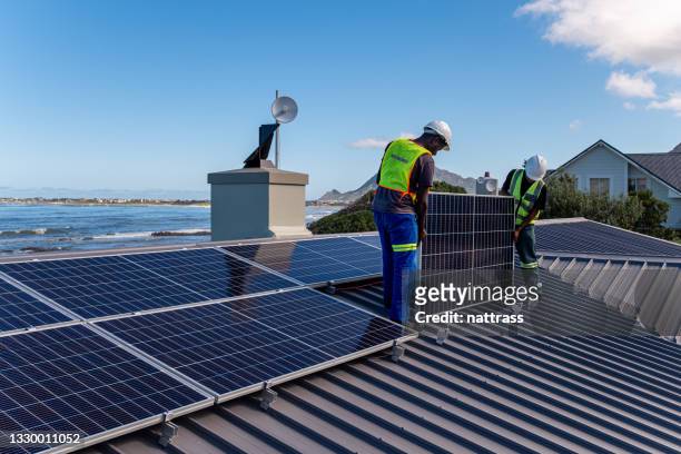two technicians install solar panels on a residential building - solkraftverk bildbanksfoton och bilder