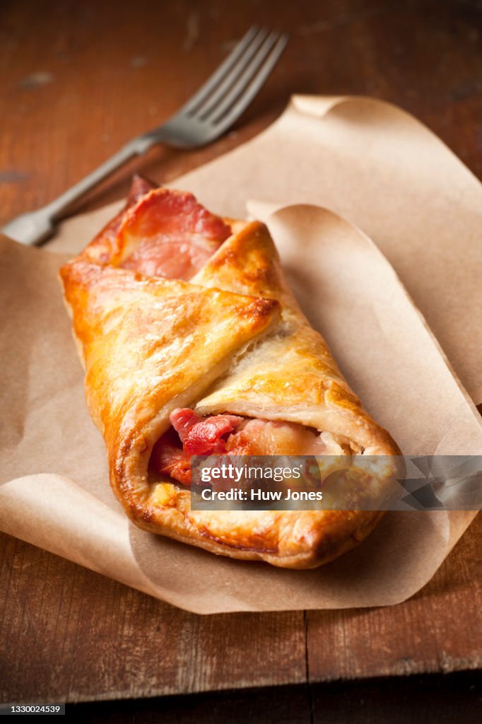 Bacon and cheese puff pastry turnover on parchment paper