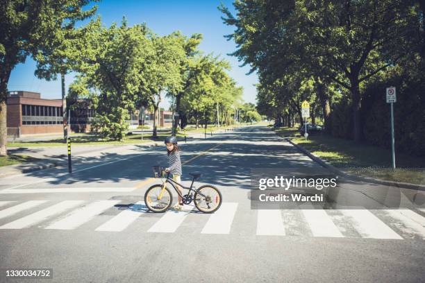 uma garotinha atravessando a estrada com sua bicicleta - travessia de pedestres marca de rua - fotografias e filmes do acervo