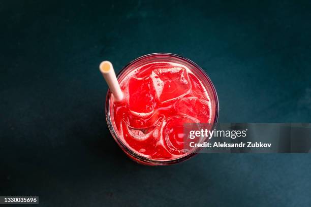 strawberry berry soft drink or cocktail with ice, with a straw in a glass glass on a wooden table in an outdoor cafe or restaurant. - soft drink stock-fotos und bilder