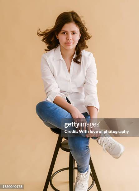 teenage girl 12-14 years old in jeans looking at camera on neutral background - 14 15 years stock-fotos und bilder