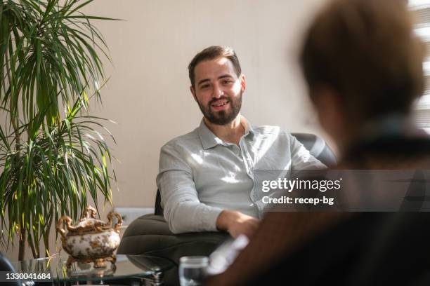 young man getting advice from female professional mental health doctor - maatschappelijk werker stockfoto's en -beelden