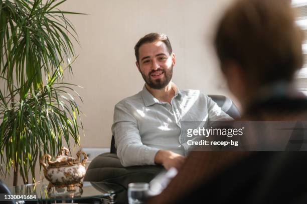 young man getting advice from female professional mental health doctor - psychotherapy stock pictures, royalty-free photos & images