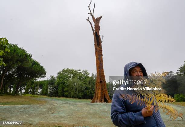 Chinese artist and dissident activist Ai Weiwei holds a fern while standing in front "Pequi Tree" , a 32 meters sculpture molded from a 1200 years...