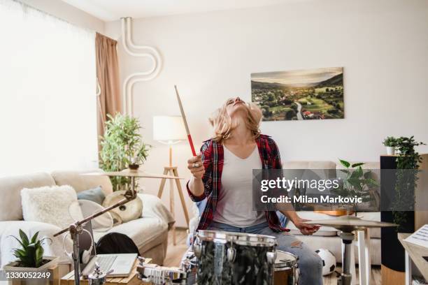 eine junge frau in freizeitkleidung spielt in ihrer wohnung akustische trommeln. - drums stock-fotos und bilder