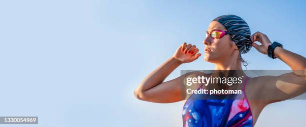 one strong athletic young woman fixing her swimming goggles - swimming competition stock pictures, royalty-free photos & images