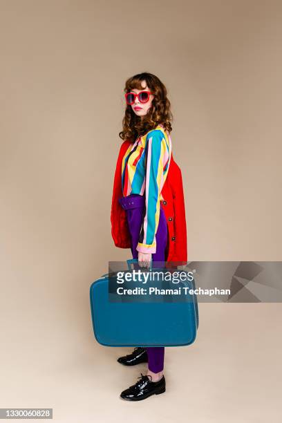 fashionable woman standing in front of plain background - woman suitcase stock pictures, royalty-free photos & images