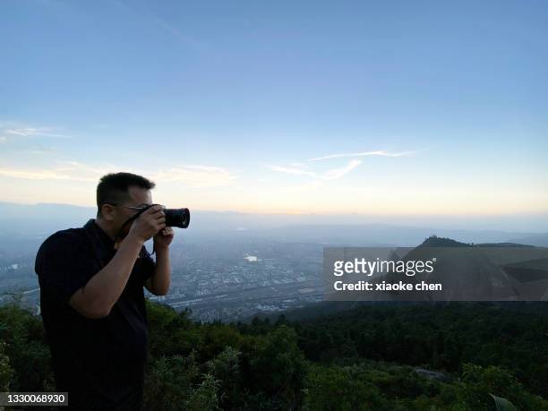 turista masculino usando cámara para tomar fotos en la cima de la montaña - fuzhou fotografías e imágenes de stock