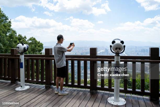 市内のガゼボで彼の携帯電話で写真を撮る男性観光客 - 福州市 ストックフォトと画像