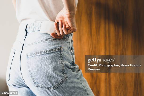 rear view of a woman wearing denim trousers - women jeans stock pictures, royalty-free photos & images