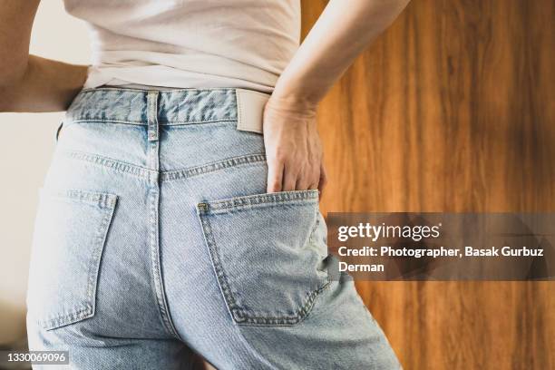 rear view of a woman wearing denim trousers - hands in pockets stock-fotos und bilder