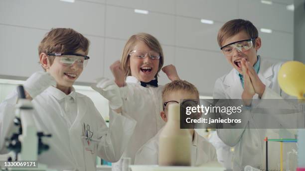des garçons curieux menant des expériences scientifiques. intérieur de laboratoire, bouillonnant, liquide mousseux. célébrer le succès - activité extra scolaire photos et images de collection