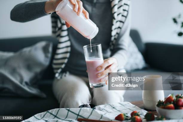 cropped shot of young asian woman making healthy homemade strawberry smoothie with electric blender at home, pouring smoothie into glass. healthy eating and healthy lifestyle concept - soya milk stock pictures, royalty-free photos & images