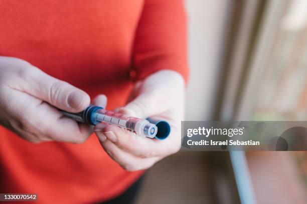 close-up view of an unrecognizable young caucasian woman preparing her insulin syringe. - insulin stock pictures, royalty-free photos & images