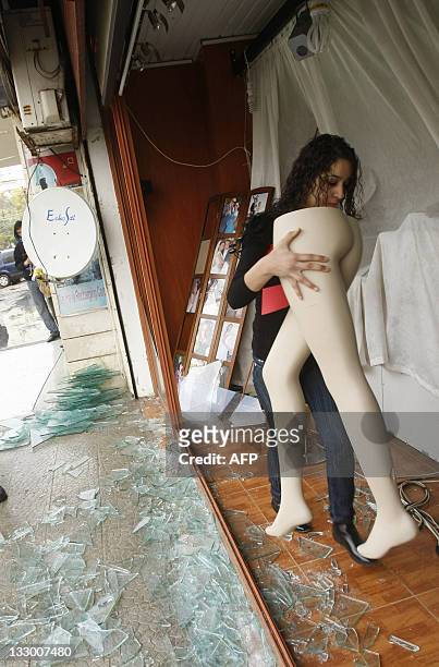 Lebanese woman removes a display mannequin from the shattered window of a photo studio located next to the Elissa Queen Hotel on the seafront of the...