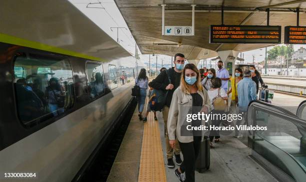 Mask-clad travelers rush to board an Alfa Pendular train to Lisbon in Campanha station during the COVID-19 Coronavirus pandemic on July 22, 2021 in...