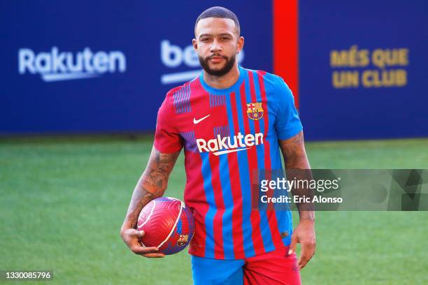 Memphis Depays of FC Barcelona reacts whilst posing for a photograph as he is presented as a FC Barcelona player at Camp Nou stadium on July 22, 2021...