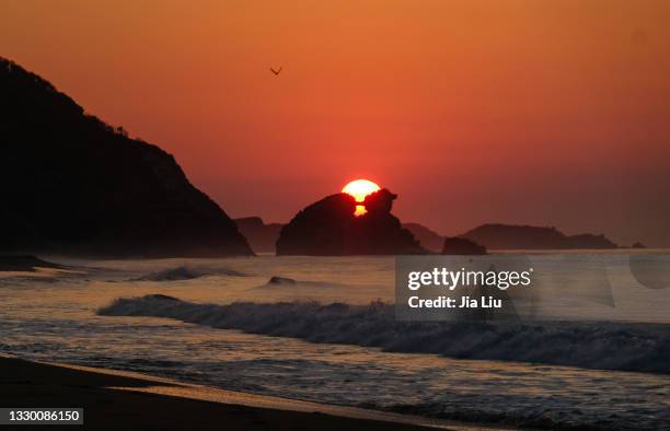 pacific sunrise through a rock - winter solstice stock-fotos und bilder