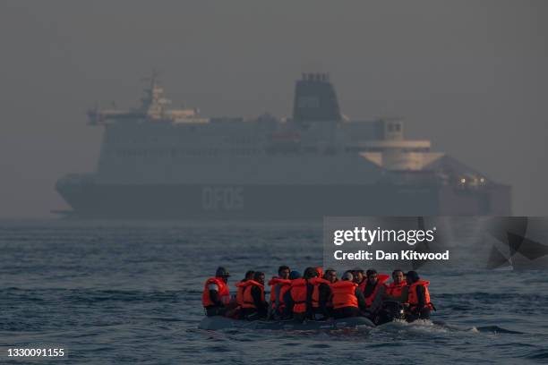 An inflatable craft carrying migrant men, women and children crosses the shipping lane in the English Channel on July 22, 2021 off the coast of...