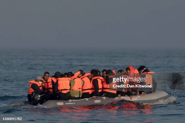 An inflatable craft carrying migrant men, women and children crosses the shipping lane in the English Channel on July 22, 2021 off the coast of...