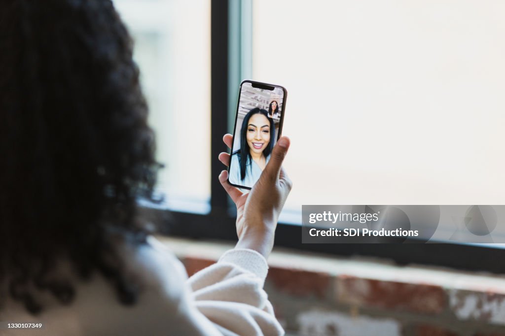 Woman video chats with colleague using smart phone
