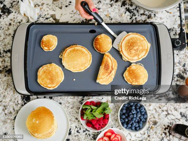 frau kocht pfannkuchen frühstück in einer hausküche - gusseiserne pfanne stock-fotos und bilder