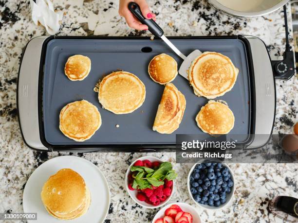 woman cooking pancake breakfast in a home kitchen - griddle stock pictures, royalty-free photos & images