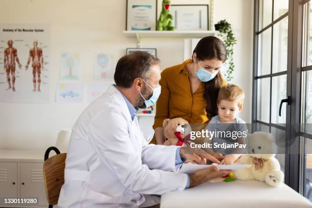 mother with protective face mask and baby son at a doctor´s appointment - doctor child stock pictures, royalty-free photos & images