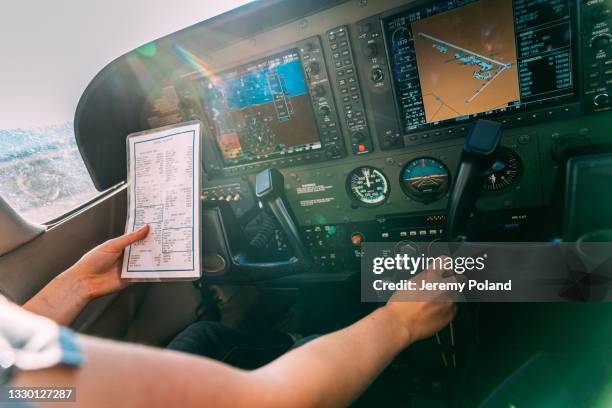 young adult female pilot consults a preflight checklist while adjusting the mixture control on a small single engine airplane - pilot cockpit checklist imagens e fotografias de stock